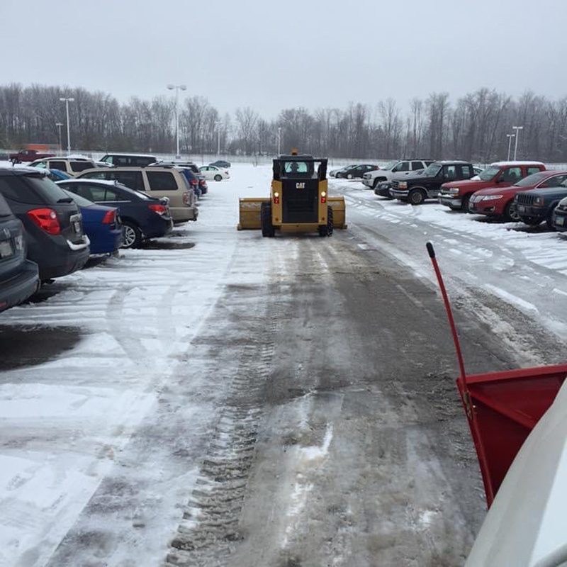 little tractor cleaning a parking lot of snow