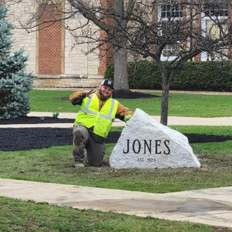 man standing by a rock with name on it